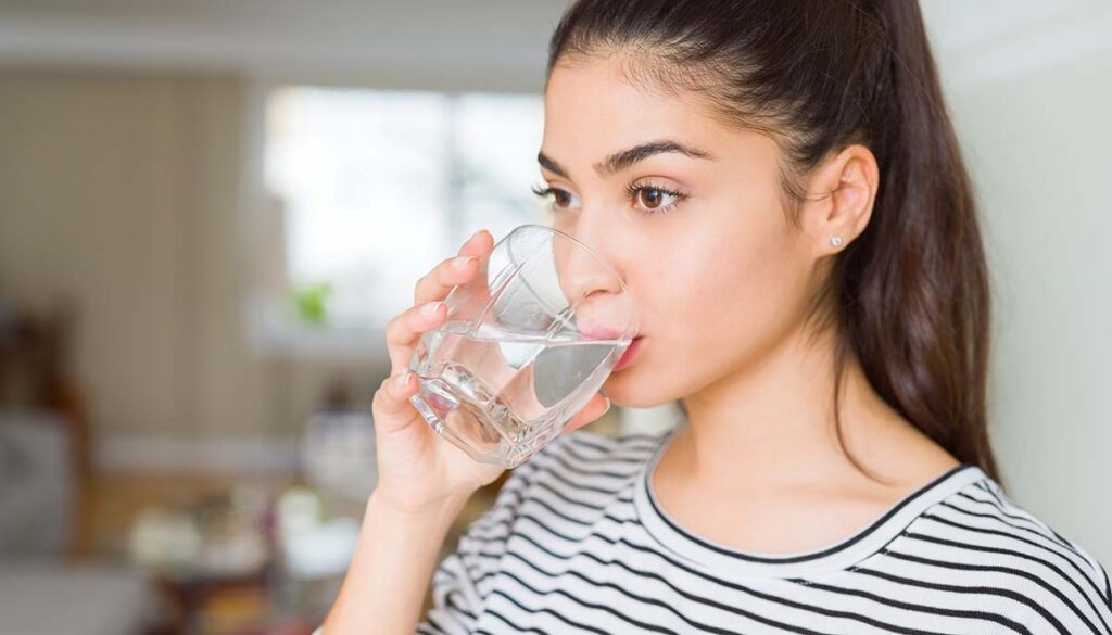 woman drinking a fresh glass of water at home