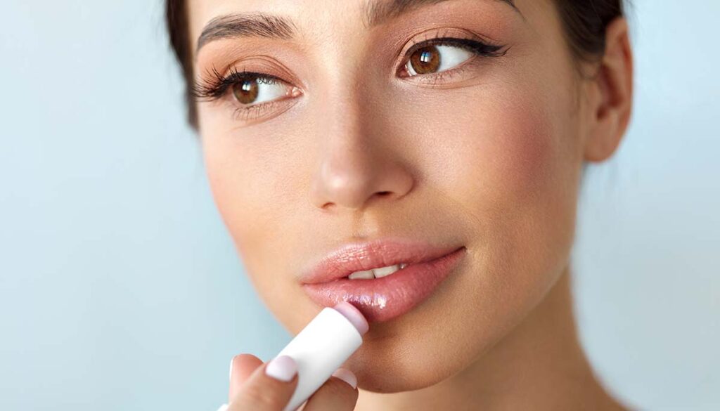 close up of woman putting on lip balm