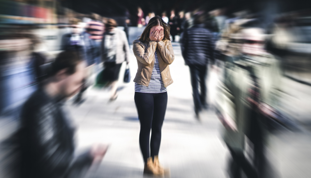 Stressed woman in crowd standing with crowd blurry around her