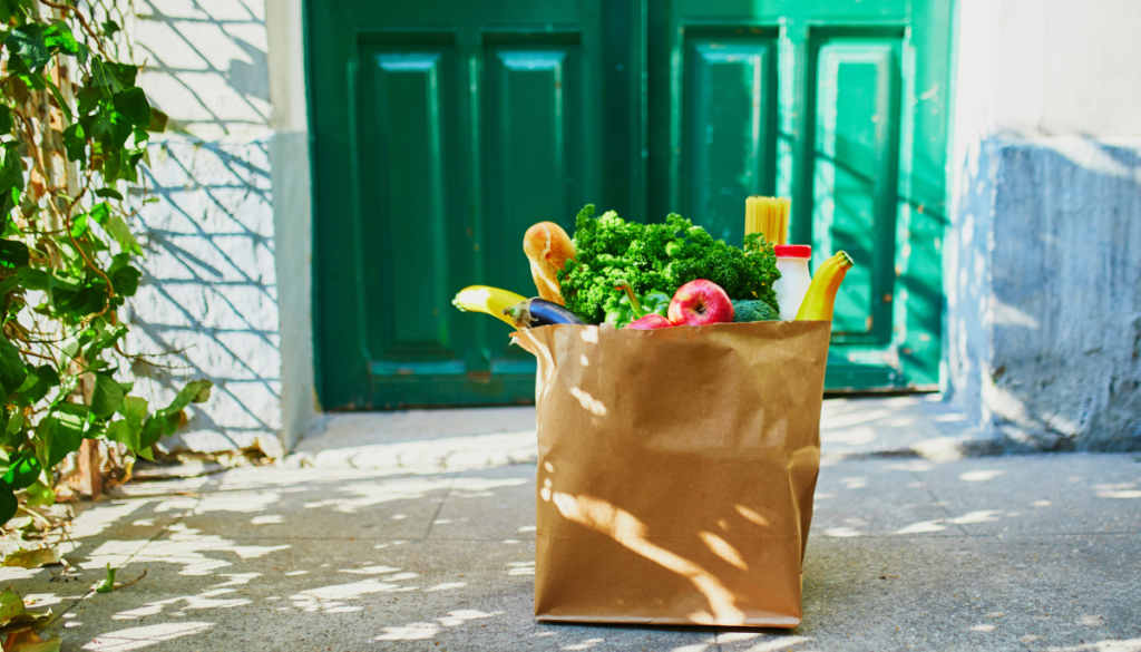 Brown bag of groceries in front of emerald green front doors