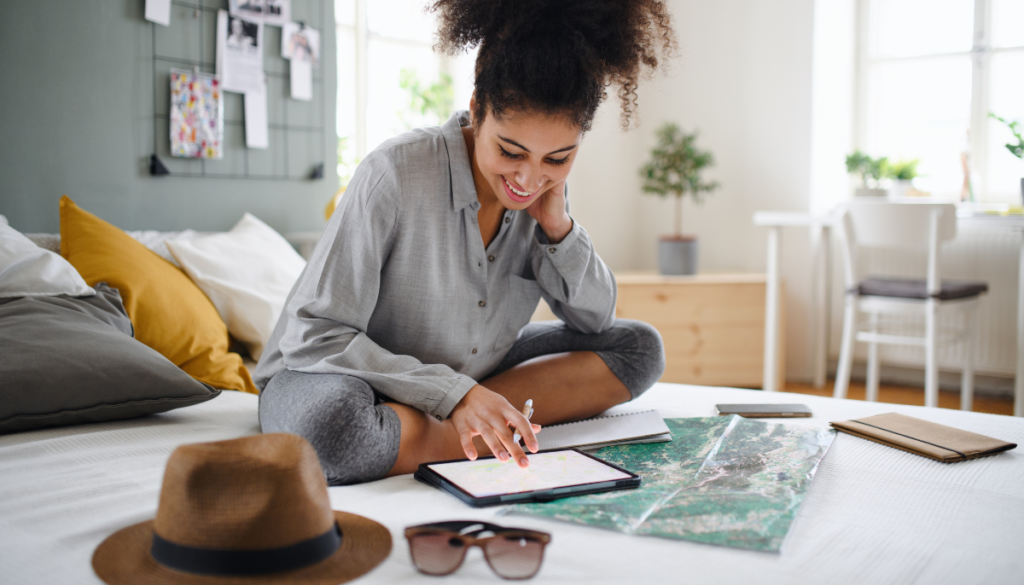 Smiling woman sitting on bed planning next vacation