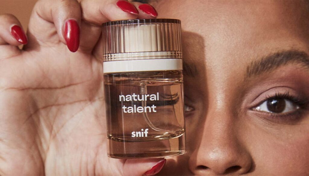 woman holding Snif Natural Talent perfume bottle up to face