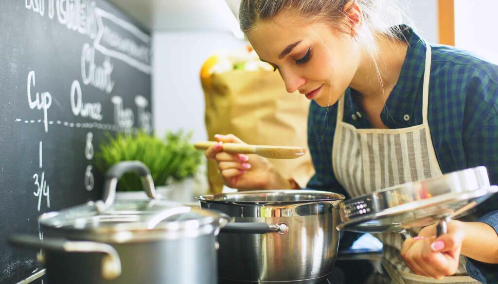 woman looking in pot on stove, cooking