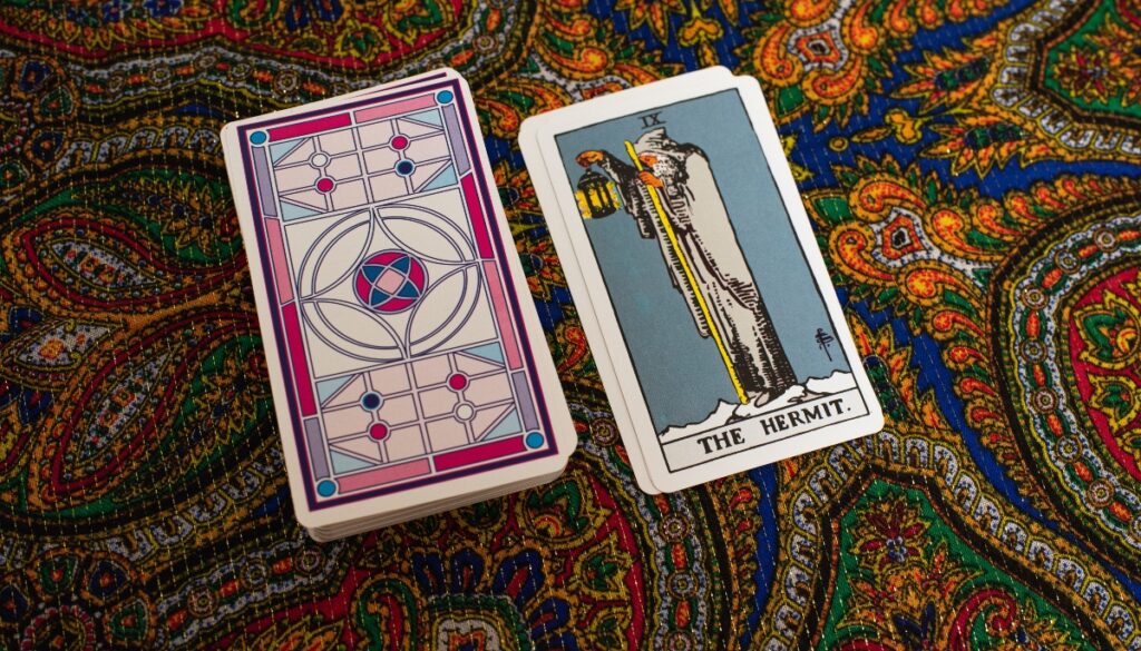 the hermit card next to a deck of cards