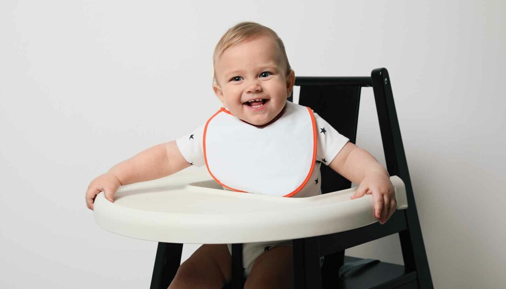 baby in a high chair wearing a bib