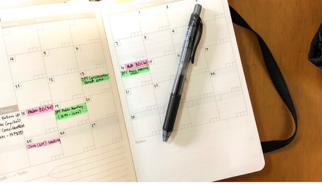 Black pen on top of planner open to month view