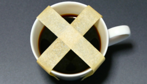 Masking tape in shape of x over the top of a mug of coffee