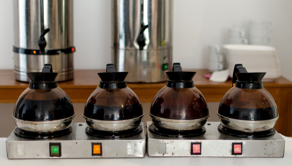 Four coffee carafes sitting on heater