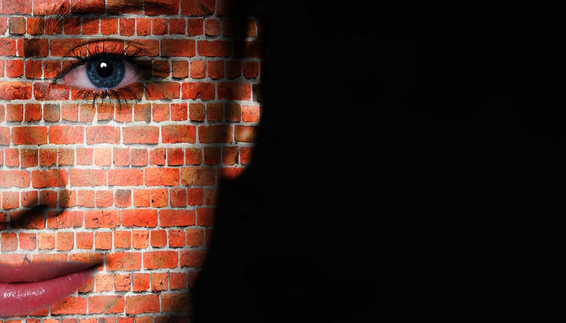 Woman face covered with brick wall pattern to represent a skin barrier while she stands against a black background