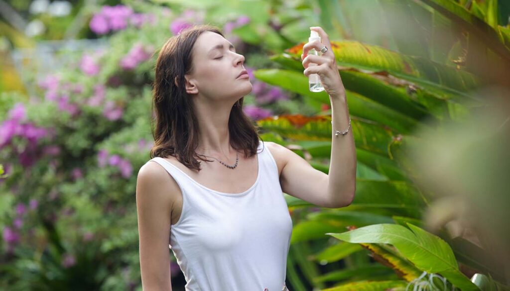 Woman spraying facial mist on her face during summertime 