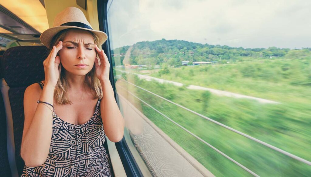 stressed woman applying pressure to her temples on a train