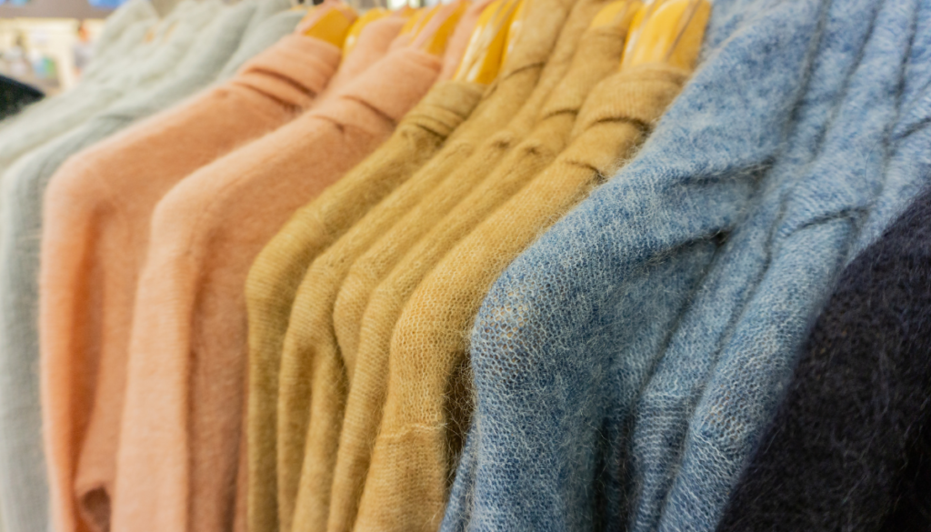 Brightly colored sweaters on hangers