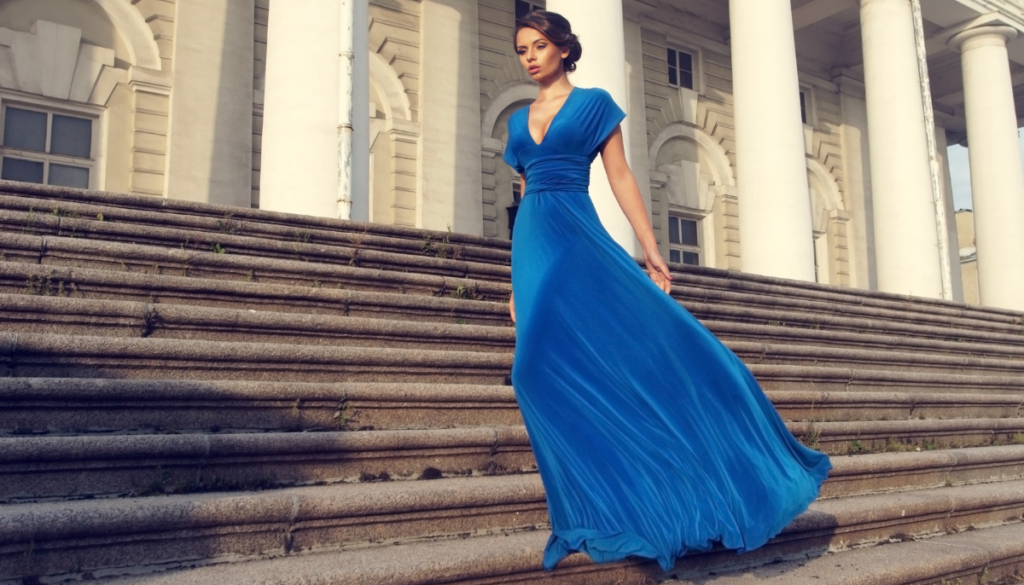 Woman in a long bright blue dress stands near steps