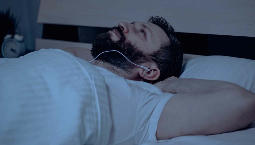 man listening to music in bed
