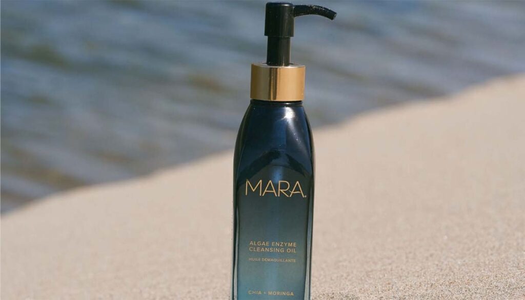 mara cleansing oil sitting in the sand on a beach 