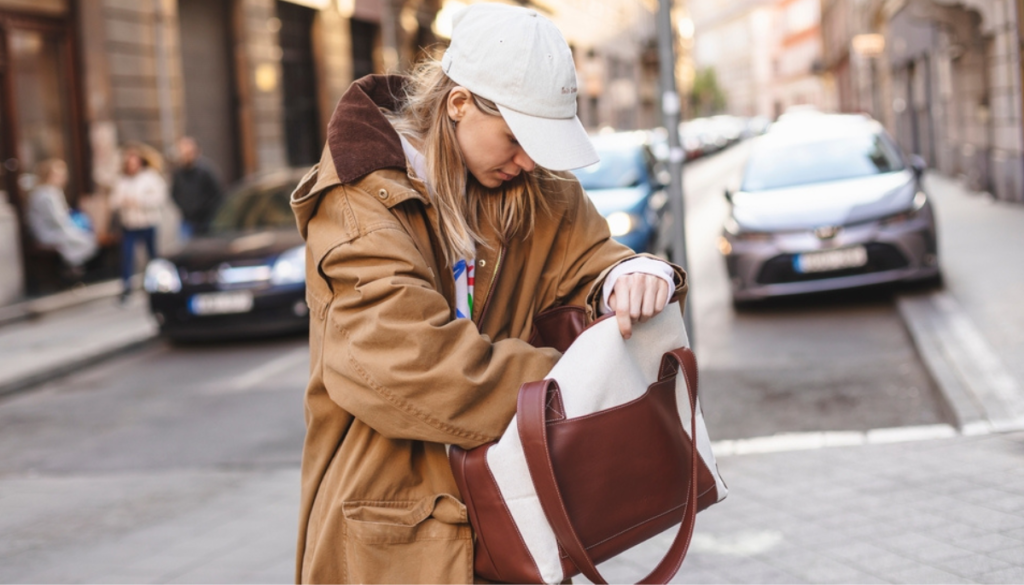 Woman on city sidewalk looking through purse