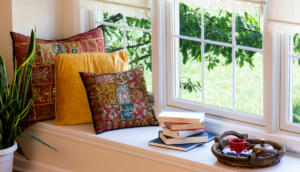 Window seat with pillows, stack of books, and tray