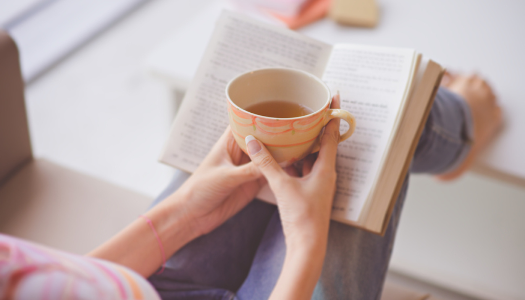 Woman holding tea in front of book