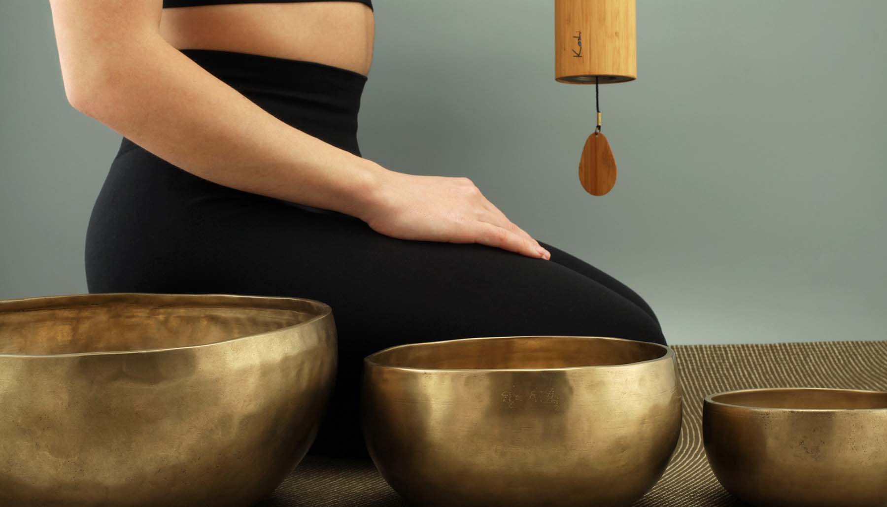 sound bath instructor with gold bowls and wind chime
