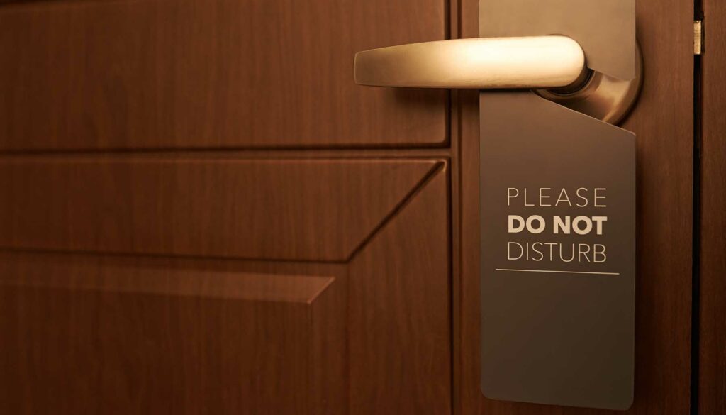 Closed door of hotel room with please do not disturb sign