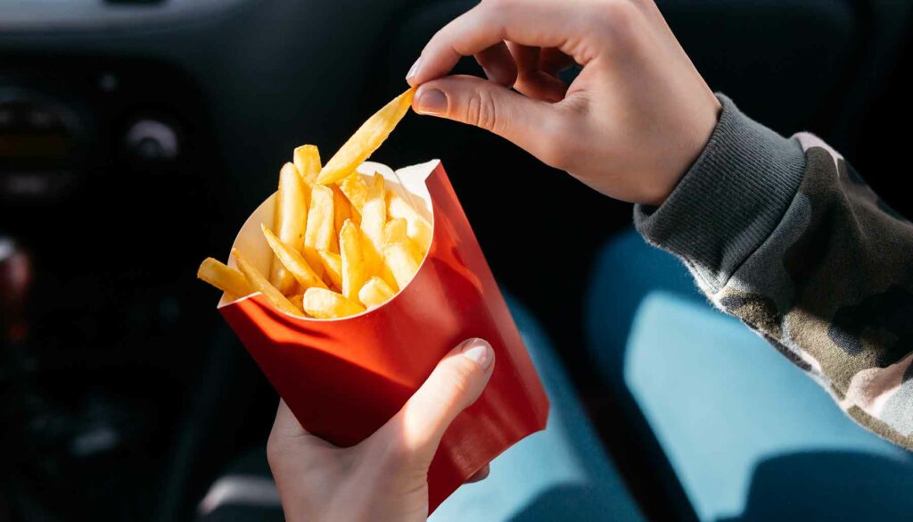 eating fast food french fries in the car