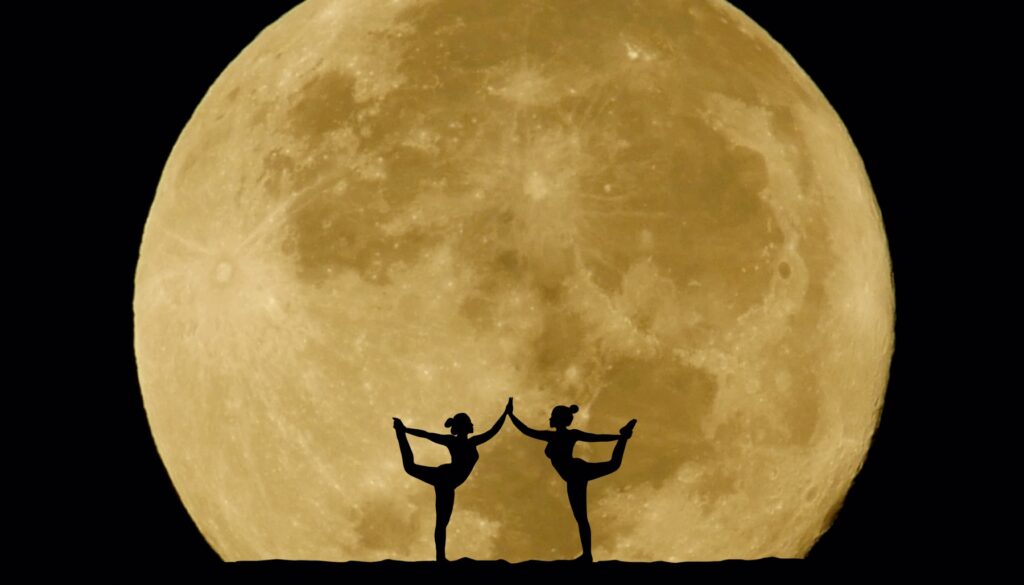 two people doing yoga in front of a full moon