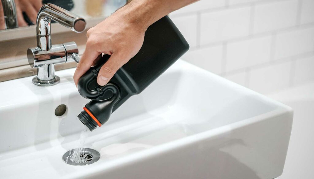 pouring drain cleaner into a bathroom sink drain