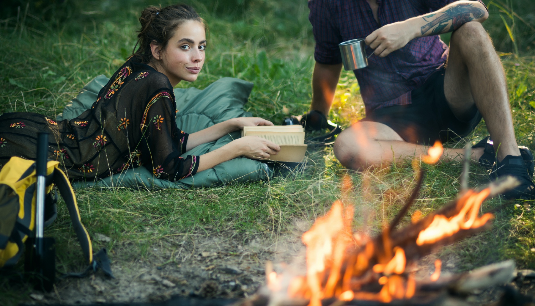 a woman reading by a bonfire