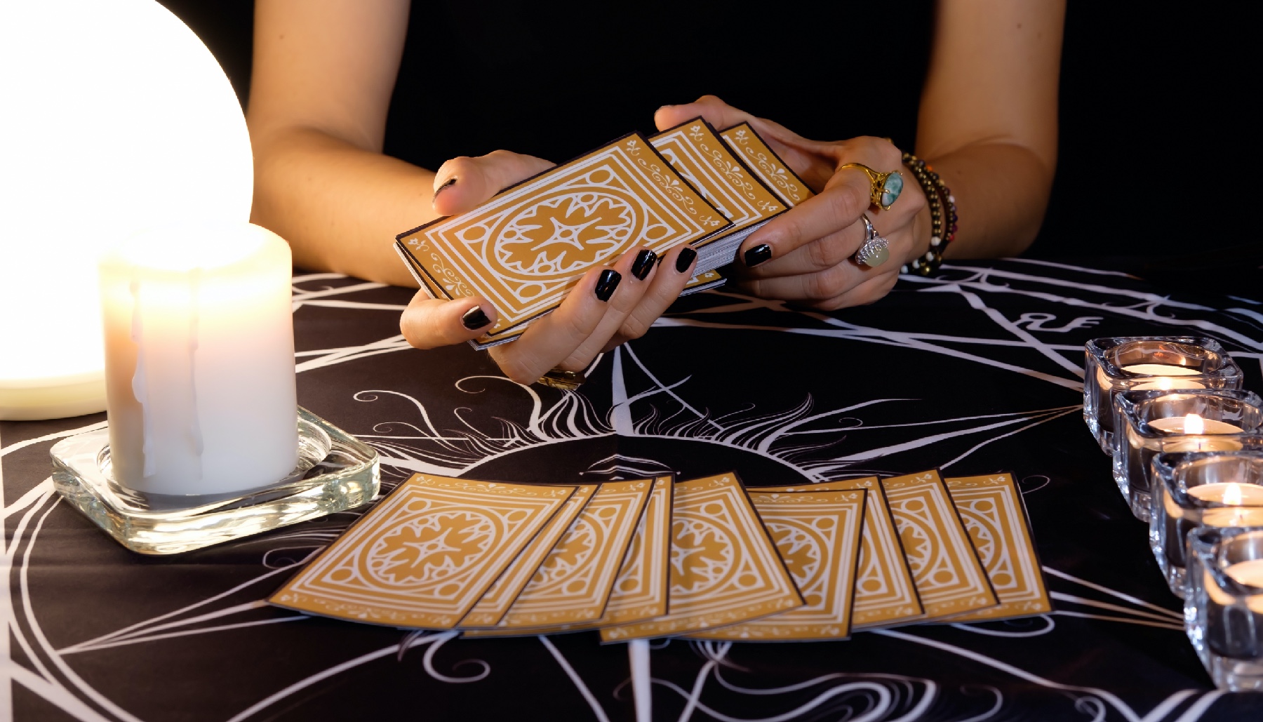 hands shuffling tarot cards next to a white candle
