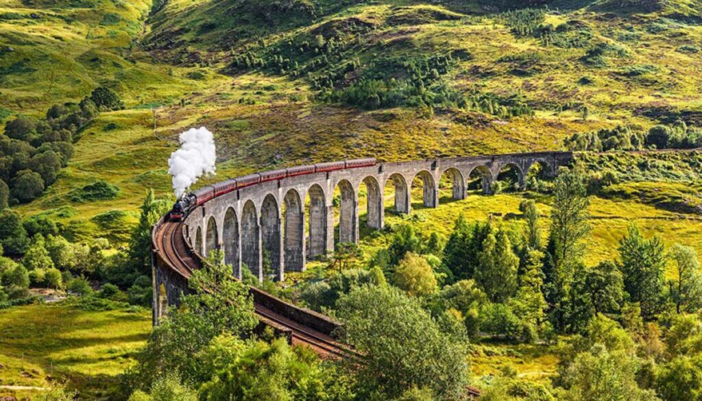 Jacobite steam train passing over greenery in Scotland