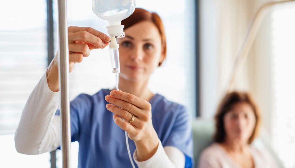 nurse setting up IV treatment for patient in hospital bed