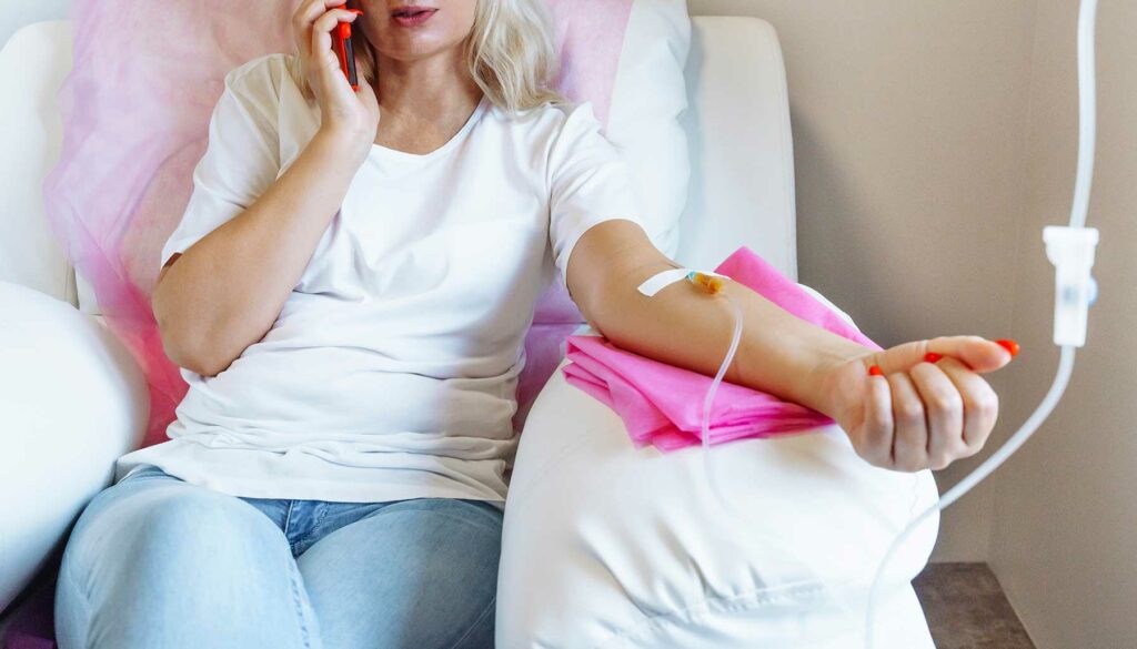 woman talking on phone while receiving IV therapy