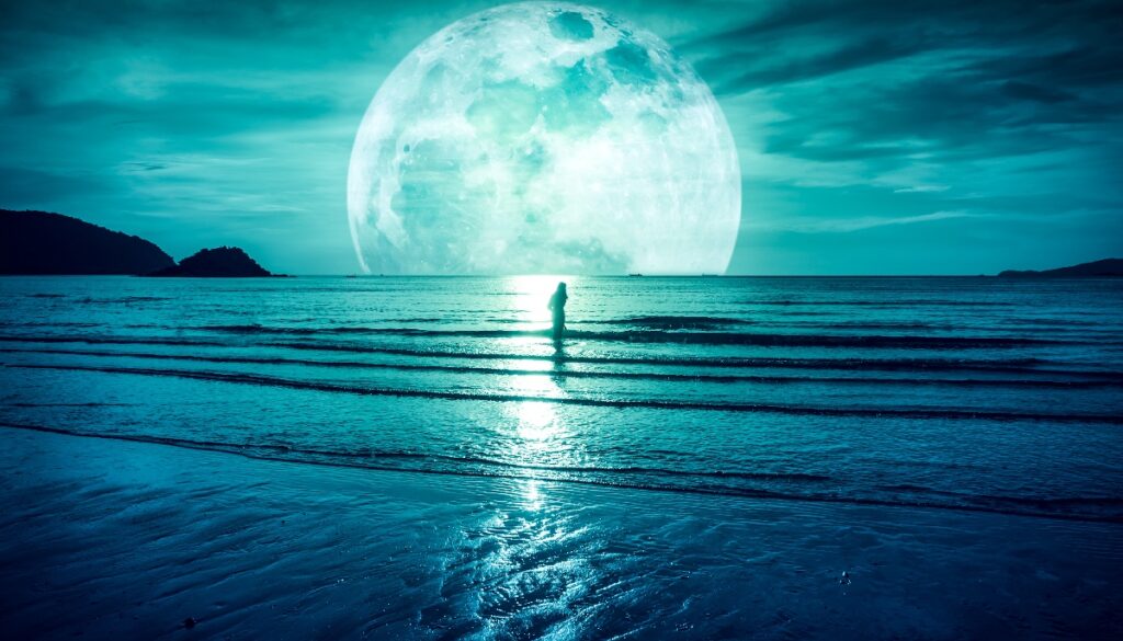 a figure standing in the ocean in front of a giant moon