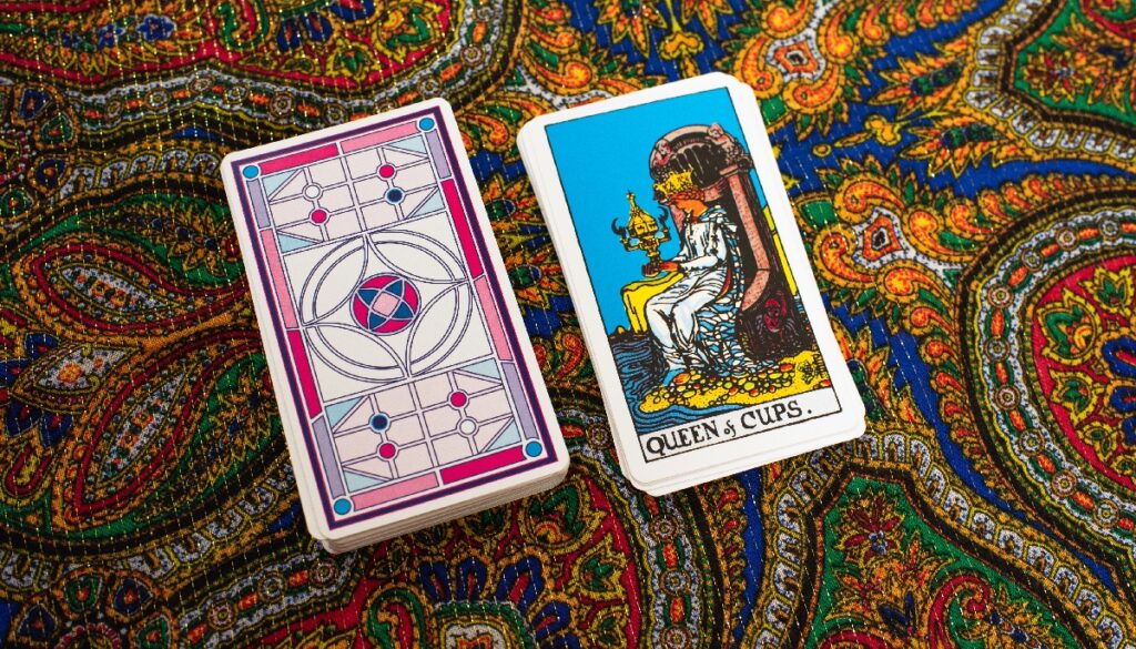 The queen of cups card next to a deck of cards