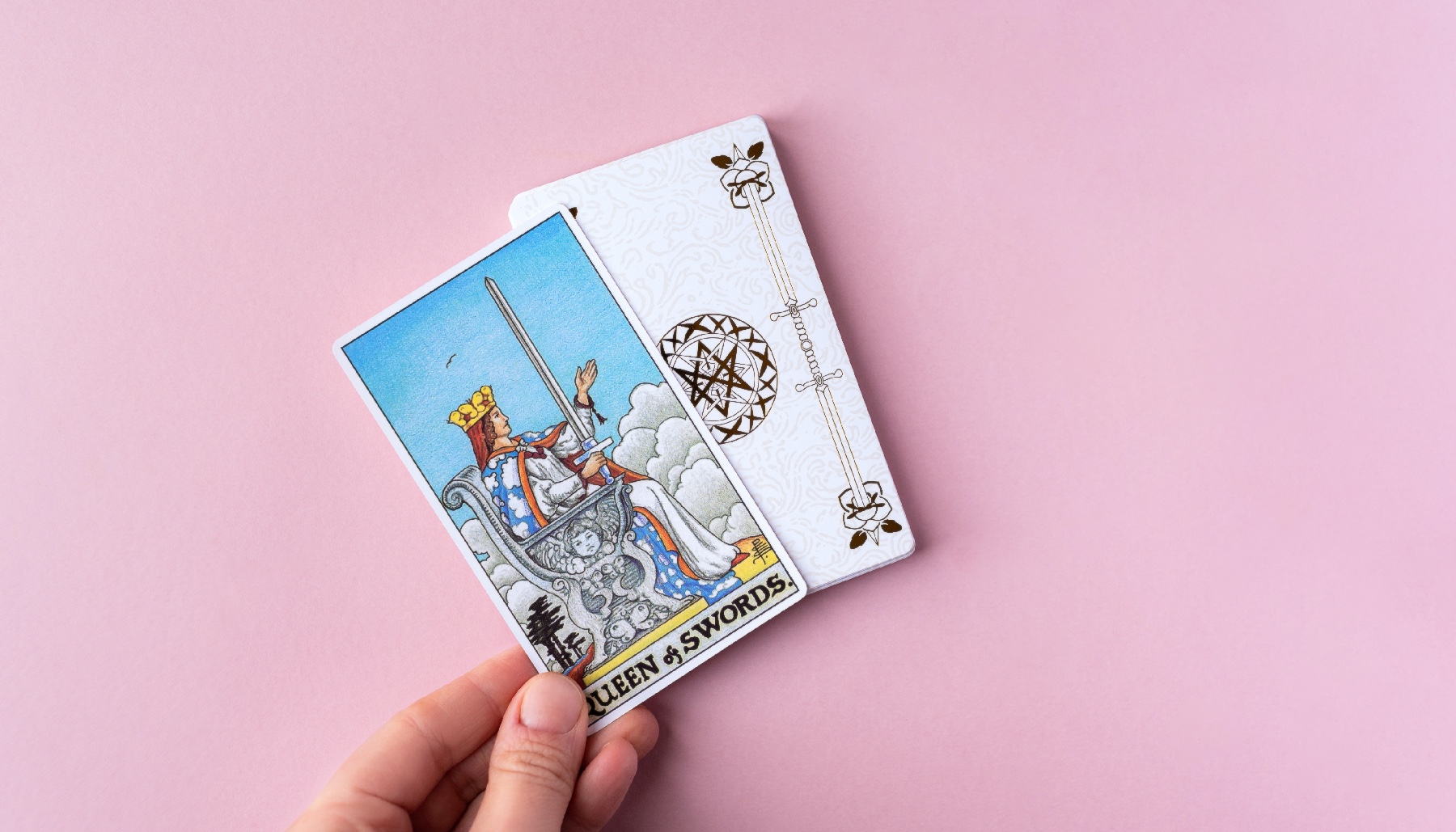 a hand holding the queen of cups card