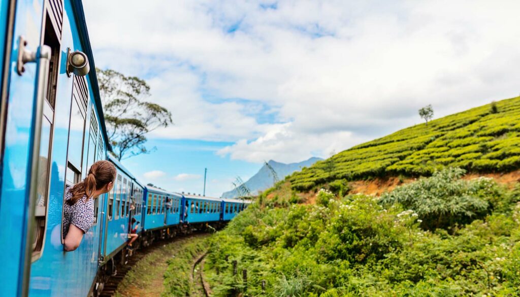 Young woman enjoying train ride from Ella to Kandy among tea plantations in the highlands of Sri Lanka
