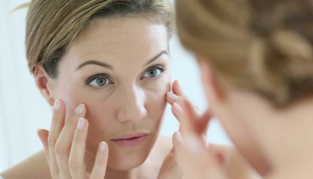 woman looking at her face in a mirror