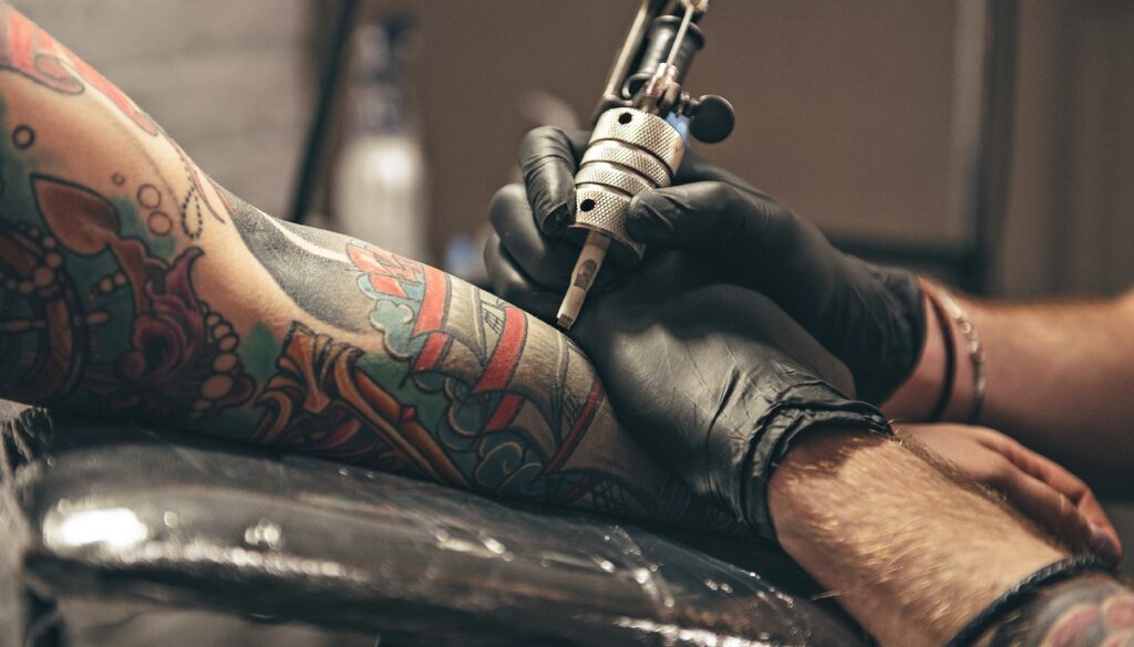An tattoo artist tattooing an arm
